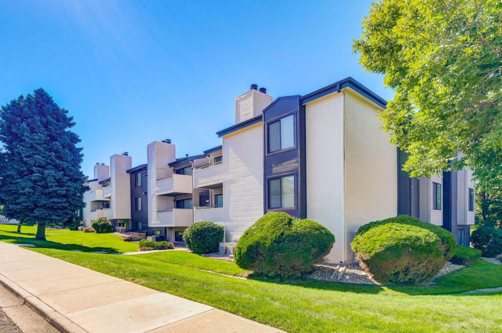 Exterior view of residential building with tree and bushes and sidewalk