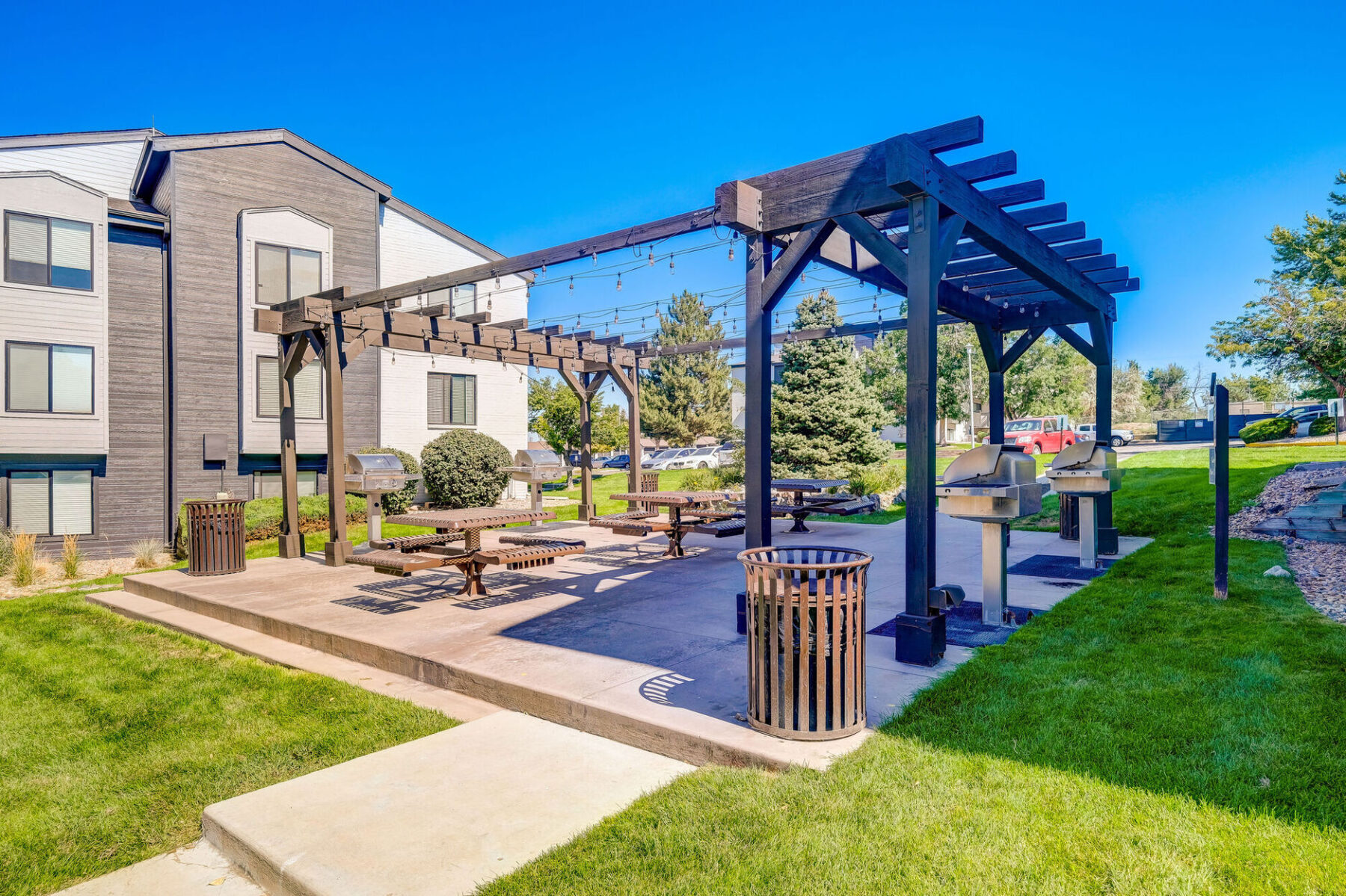 Outdoor covered grill area with picnic tables and residential buildings in the back ground