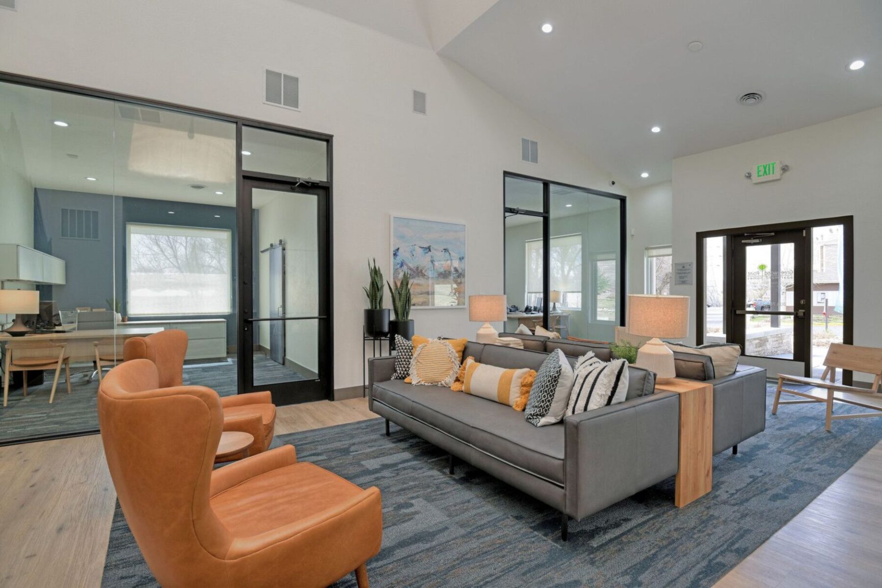 Leasing office waiting area with couches and chairs and private employee offices in the back