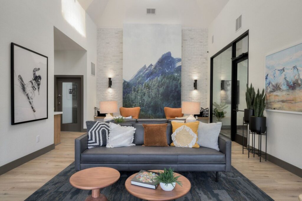 Leasing office waiting area with couches. Private employee office to the right with mural of mountain and trees in the back.