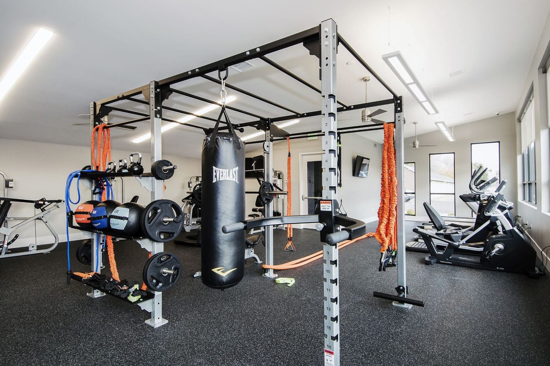 Functional training rack with punching bag, dip station, resistance bands, and battle ropes