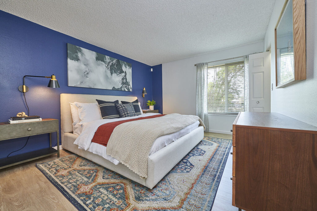 Staged bedroom with blue accent wall and large window