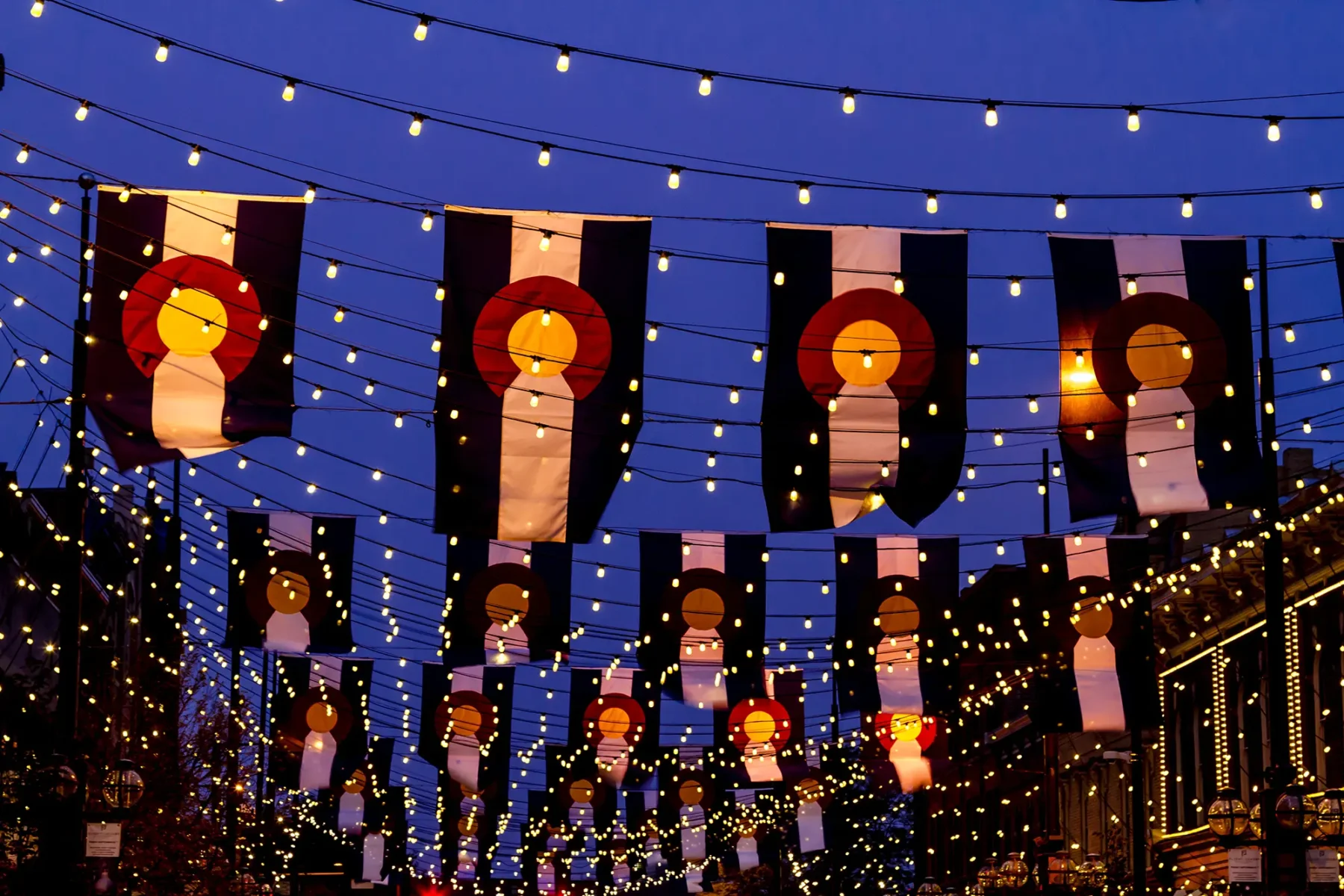 Street hung with string lights and Colorado flags